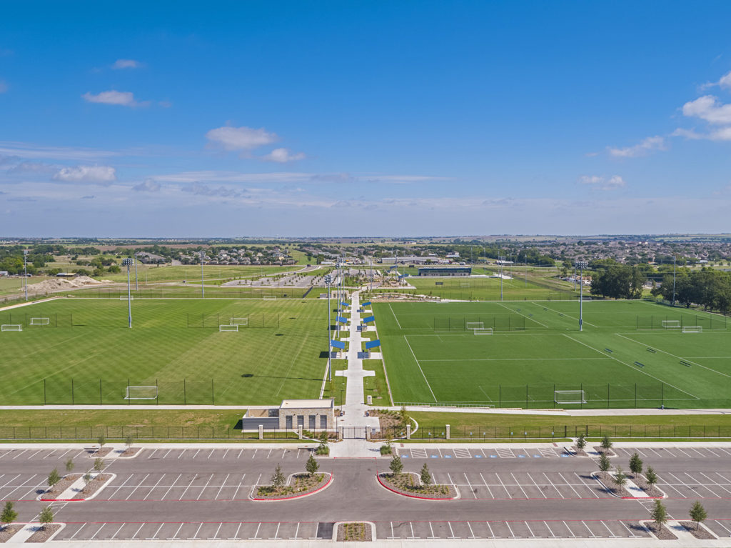 aerial view of a parking lot and fields at the round rock multipurpose complex. 