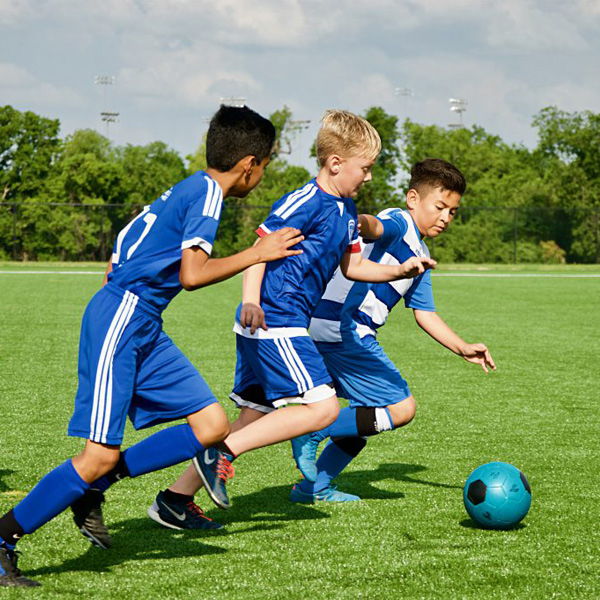 3 soccer players on field kicking ball