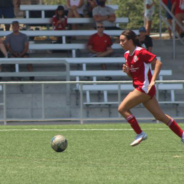 female soccer player kicking ball on field