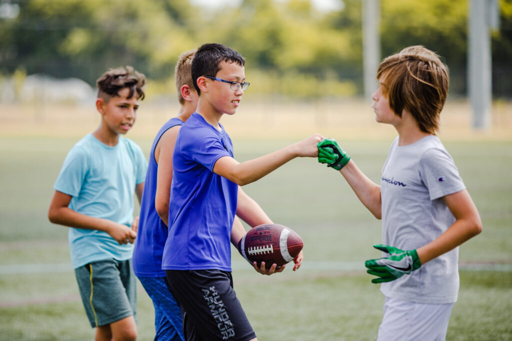 Two athletes fist-bumping at a football training program at the Round Rock Multipurpose Complex