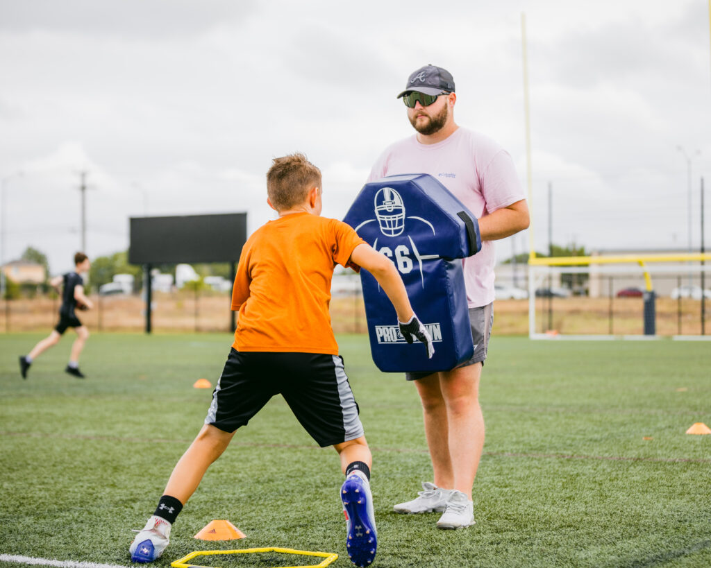 An athlete working on football blocking at a sports training program at the Round Rock Multipurpose Complex