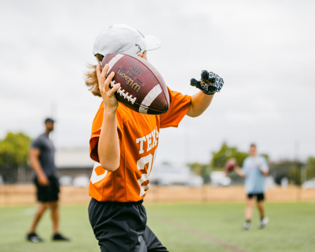 An athlete passing a football at a sports training program at the Round Rock Multipurpose Complex